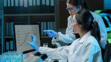 Two scientists wearing lab coats and safety glasses analyzing data displayed on a computer screen in a laboratory setting | Image Credit: © NCST Studio - © NCST Studio - stock.adobe.com