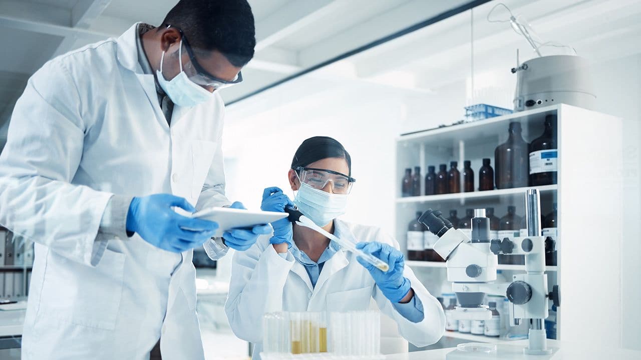 People, mask or scientists on tablet in laboratory for results, life extension or antiaging medicine. Teamwork, vial or biologists with chemistry research, test tube or science information update |Image Credit: ©peopleimages.com - ©peopleimages.com-stock.adobe.com 