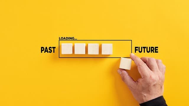 Transition of time from past to future concept. Hand places a wooden cube to the loading bar with the words past and future | Image Credit: © CAGKAN - STOCK.ADOBE.COM