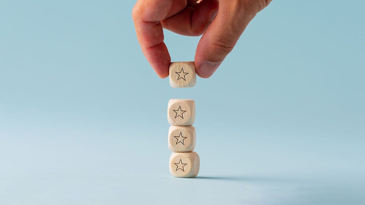 hand placing a block on top of a series of blocks with stars