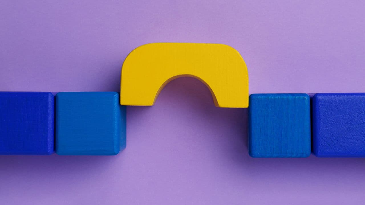 Bridge made of colorful blocks on violet background, flat lay. Connection, relationships and deal concept | Image Credit: © New Africa - stock.adobe.com