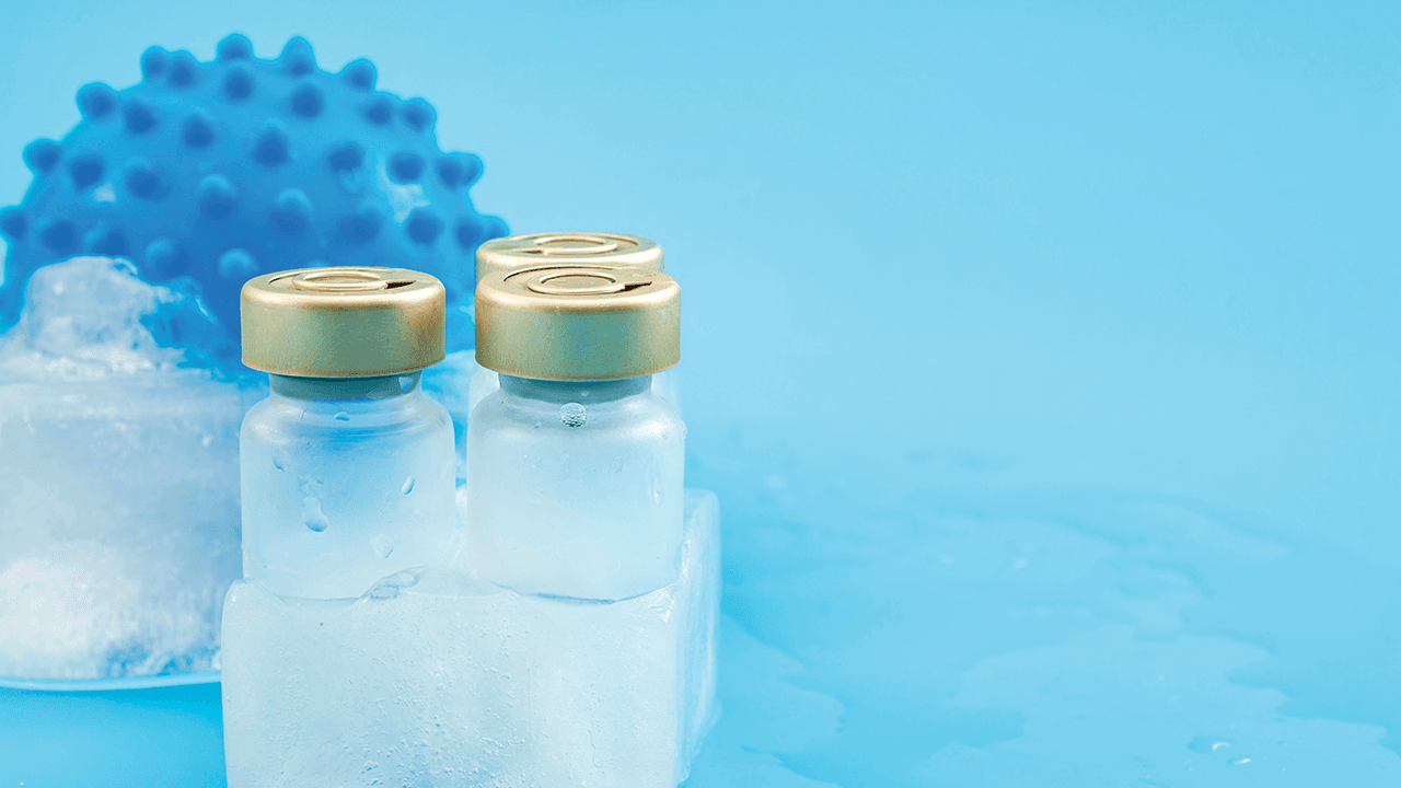 Low storage temperatures for pharmaceutical medicine, covid treatment and coronavirus vaccination concept with vaccine and virus frozen in a chunk of ice isolated on blue background with copy space | Image Credit: © Victor Moussa - © Victor Moussa - stock.adobe.com