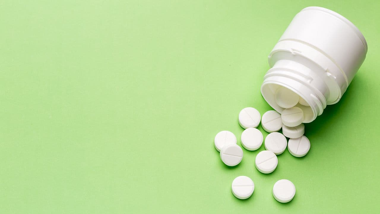 Round white pills and plastic pill bottle | Image Credit: © ironstealth - Stock.Adobe.com